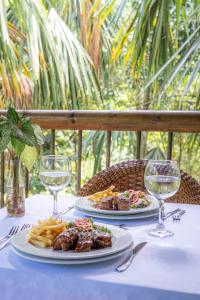 una mesa con dos platos de comida y copas de vino en Villa Maria Tayrona, Jungle and Sea Experience, en Los Naranjos