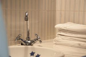 a bathroom with a sink and a faucet and towels at Apartamento Turístico El Sotanillo de Valverde de la Vera in Valverde de la Vera