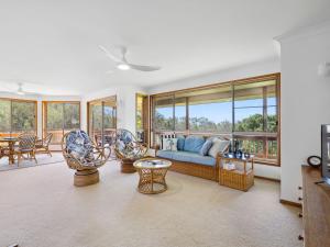 - un salon avec un canapé, des chaises et des fenêtres dans l'établissement Gerry's Mullawarra Beach House, à Arrawarra