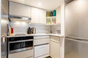 een keuken met witte kasten en een roestvrijstalen koelkast bij Rivoli Vieille du temple in Parijs