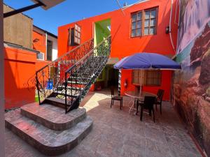 伊基克的住宿－Hotel Casa del profesor Iquique，楼梯通往带桌子和雨伞的建筑