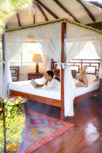 a woman laying on a bed in a bedroom at Villa Maria Tayrona, Jungle and Sea Experience in Los Naranjos