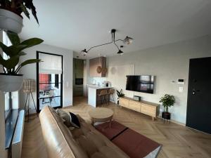 a living room with a brown couch and a kitchen at WIDOKI3 Apartment Montownia Foodhall in Gdańsk