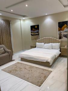 1 dormitorio con 1 cama grande y 1 silla en Happiness Place en King Abdullah Economic City