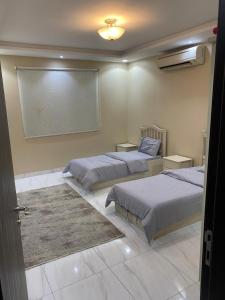 1 dormitorio con 2 camas y pantalla de proyección en Happiness Place en King Abdullah Economic City
