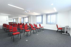 an empty room with red chairs and desks in it at Ajax Hoteis in Collatina