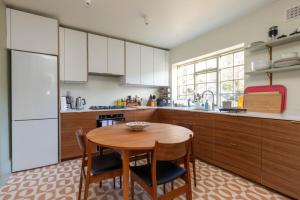 a kitchen with a wooden table and a kitchen with white cabinets at Spacious 2BD Flat By Regents Park & Camden Town! in London