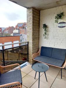 a balcony with a couch and a table on a balcony at Felix De Haan in De Haan