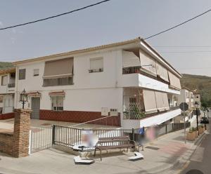 a white apartment building with a balcony and a chair at Mi Carmela in Cenes de la Vega