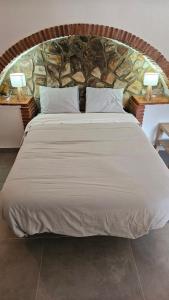 a large bed in a room with a stone wall at Cuevas CEMAR in Guadix