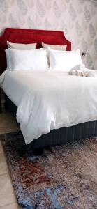 een bed met witte lakens en kussens op een tapijt bij Bakaya Hotel Tlokweng in Gaborone