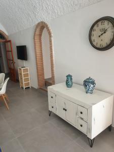 a living room with a clock and a white dresser at Cuevas CEMAR in Guadix
