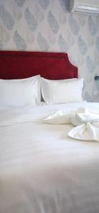 een wit bed met een rood hoofdeinde en witte kussens bij Bakaya Hotel Tlokweng in Gaborone
