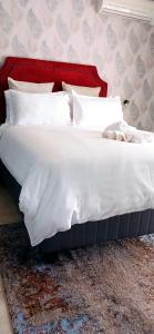 a large white bed with a red head board at Bakaya Hotel Tlokweng in Gaborone