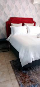 een groot bed met een rood hoofdeinde en witte kussens bij Bakaya Hotel Tlokweng in Gaborone