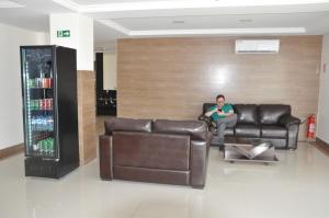 a man sitting on a leather couch in a living room at Lazzarus Hotel in Alexânia