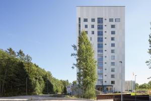 un edificio blanco alto con un árbol delante de él en Amazing views by Finnoo metro, en Espoo