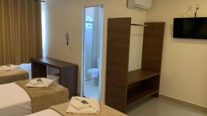 a hotel room with two beds and a toilet and a television at Lazzarus Hotel in Alexânia