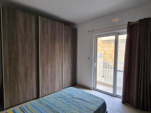 a bedroom with a bed and a sliding glass door at Cescaren Gozo Ghajnsielem in Għajnsielem