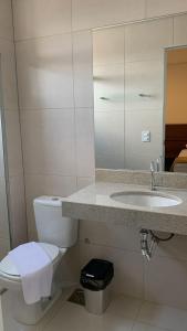 a white bathroom with a toilet and a sink at Lazzarus Hotel in Alexânia
