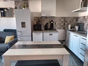 a kitchen with a white refrigerator and a table at Chez Fifi au Barcarès in Le Barcarès