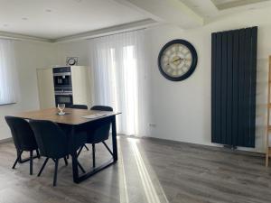 ein Esszimmer mit einem Tisch und einer Uhr an der Wand in der Unterkunft Apartments Metzingen Panoramablick in Metzingen