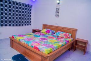 um quarto com uma cama de madeira com lençóis coloridos em Oluwa-sheyi Apartment em Cotonou