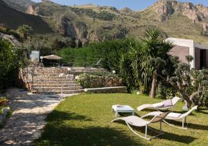 two chairs and a table in a yard with mountains at Villa Antico Pozzo piscina privata SPA in Castellammare del Golfo