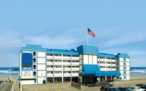 a hotel on the beach with an american flag on top at Promenade Inn & Suites Oceanfront in Seaside