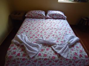 a bed with a blanket and pillows on it at Pousada Maria Francisca in Santa Bárbara