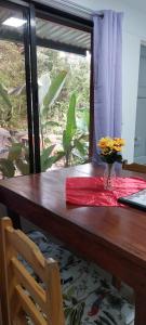 a wooden table with a vase of flowers on it at Corcovado & Drake Inn in Drake