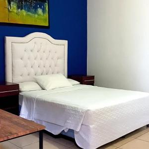 a bedroom with a white bed with a blue wall at Los Vados Hotel in Managua