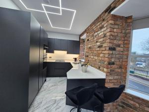 una cocina con armarios negros y una pared de ladrillo en Spectrum Apartments, en Clooney Park