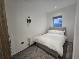 1 dormitorio con 1 cama con sábanas blancas y ventana en Spectrum Apartments, en Clooney Park