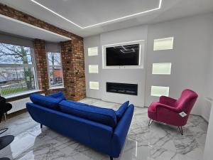 sala de estar con sofá azul y 2 sillas rojas en Spectrum Apartments, en Clooney Park