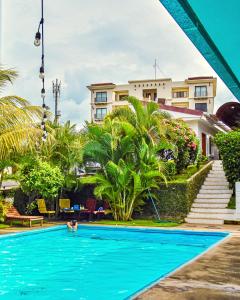 a man swimming in a swimming pool in front of a house at Los Vados Hotel in Managua