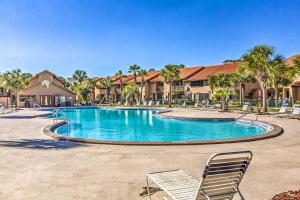 einen Pool in einem Resort mit Stühlen und Palmen in der Unterkunft Panama City Beach Townhome with Resort Amenities! in Panama City Beach