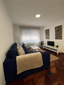 a living room with a blue couch and a television at O fogar do camiñante in Redondela