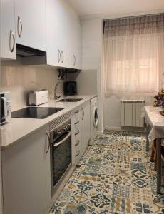 a kitchen with white cabinets and a tile floor at O fogar do camiñante in Redondela