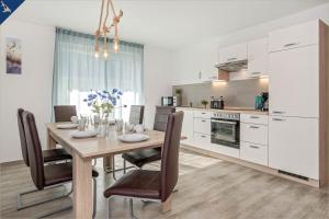 a kitchen with a wooden table with chairs and a dining room at Ferienanlage Sonneninsel Strandmöwe Erdgeschoss in Loddin