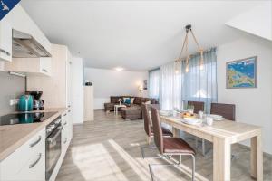 eine Küche und ein Wohnzimmer mit einem Holztisch und Stühlen in der Unterkunft Ferienanlage Sonneninsel Haus Himmelblau Obergeschoss in Loddin