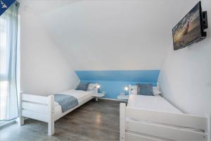 1 Schlafzimmer mit 2 Betten und einem TV an der Wand in der Unterkunft Ferienanlage Sonneninsel Haus Himmelblau Obergeschoss in Loddin