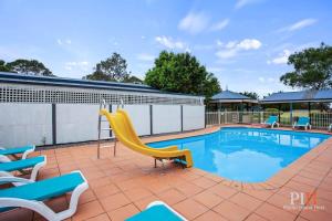 uma piscina com cadeiras e um escorrega amarelo em Phillip Island Family Resort 2Bdr em Cowes