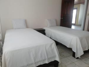duas camas com lençóis brancos num quarto em Alojamiento David em David