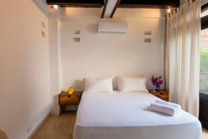 a bedroom with a white bed and a window at Casa Familiar - Maria de las Palmas -Getsemani in Cartagena de Indias