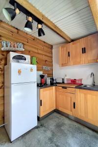 La cuisine est équipée d'un réfrigérateur blanc et de placards en bois. dans l'établissement Ti Grounouy, au Diamant