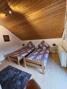 two beds in a room with a wooden ceiling at Schön und bequem Wohnung in Althengstett