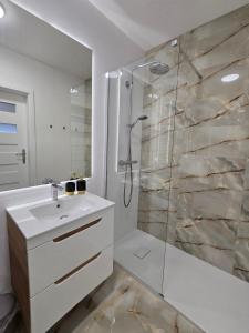 ein weißes Bad mit einer Dusche und einem Waschbecken in der Unterkunft Ekskluzywny apartament + garaż in Krakau