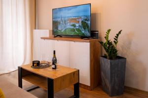 ein Wohnzimmer mit einem TV und einem Tisch mit einer Flasche Wein in der Unterkunft Ekskluzywny apartament + garaż in Krakau