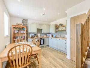 una cucina con armadi bianchi e tavolo e sedie in legno di Horseshoe Cottage historic gem near Snowdonia. a Caernarfon